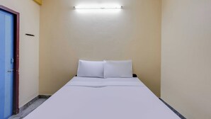 Kapea käytävä, jonka päässä on sänky, vasemmalla puolella ovi ja katossa kattotuuletin.
