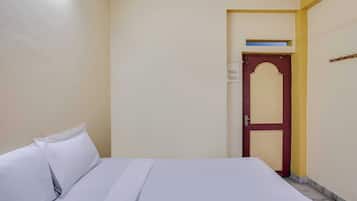 Et hotelværelse med en seng, en dør og en lampe monteret på væggen.