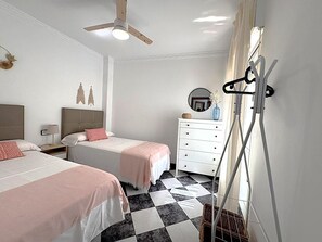 A hotel room with two beds, a white dresser, a ceiling fan, and a checkered floor. - Nerja Sun Apartments Diputación 8 Center (Nerja)