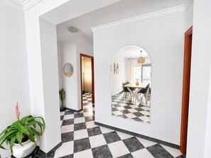 A hallway with a checkered floor leading to a dining area with a table and chairs. - Nerja Sun Apartments Diputación 8 Center (Nerja)