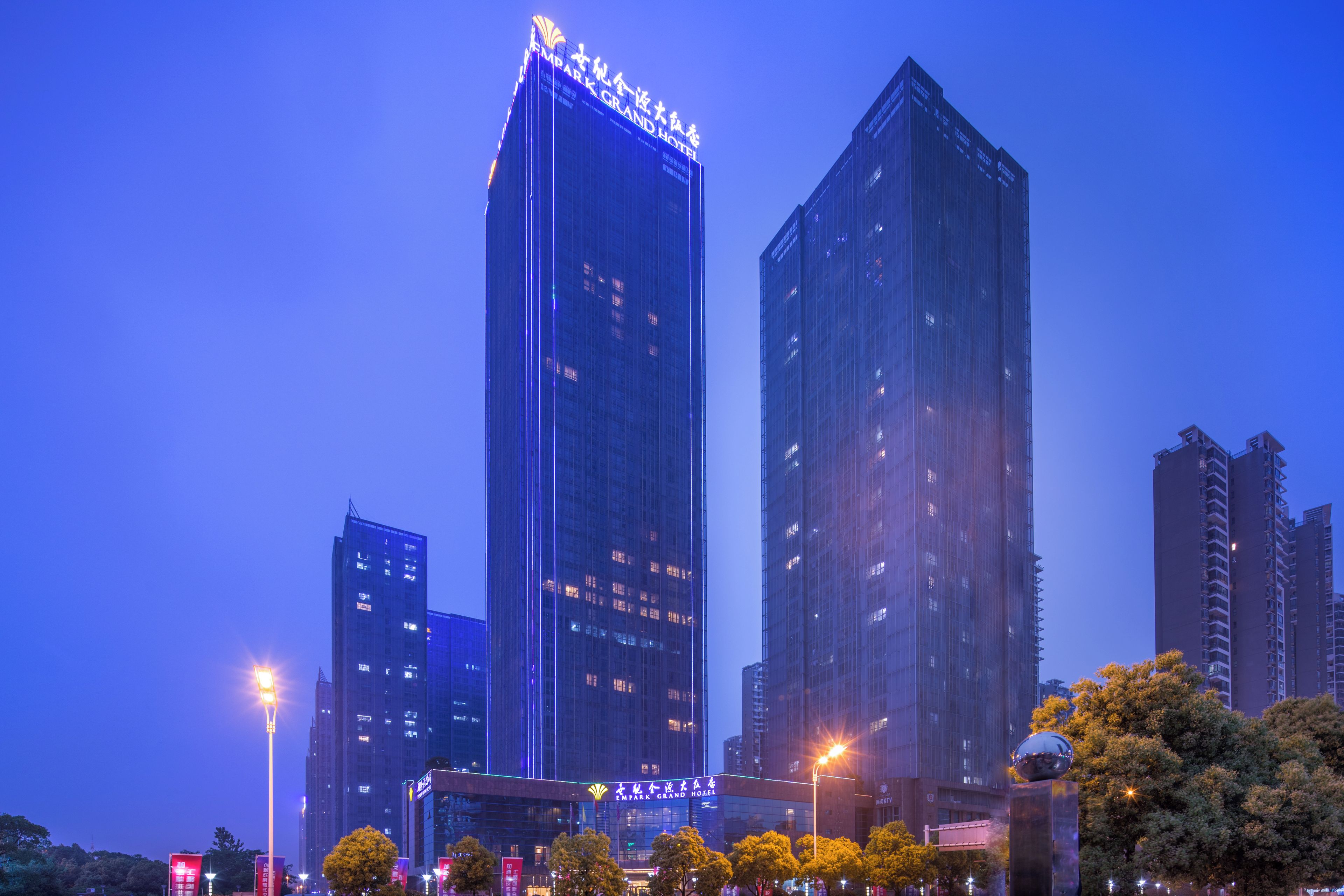 Un hotel de gran altura con señalización iluminada, rodeado de otros edificios altos y farolas.