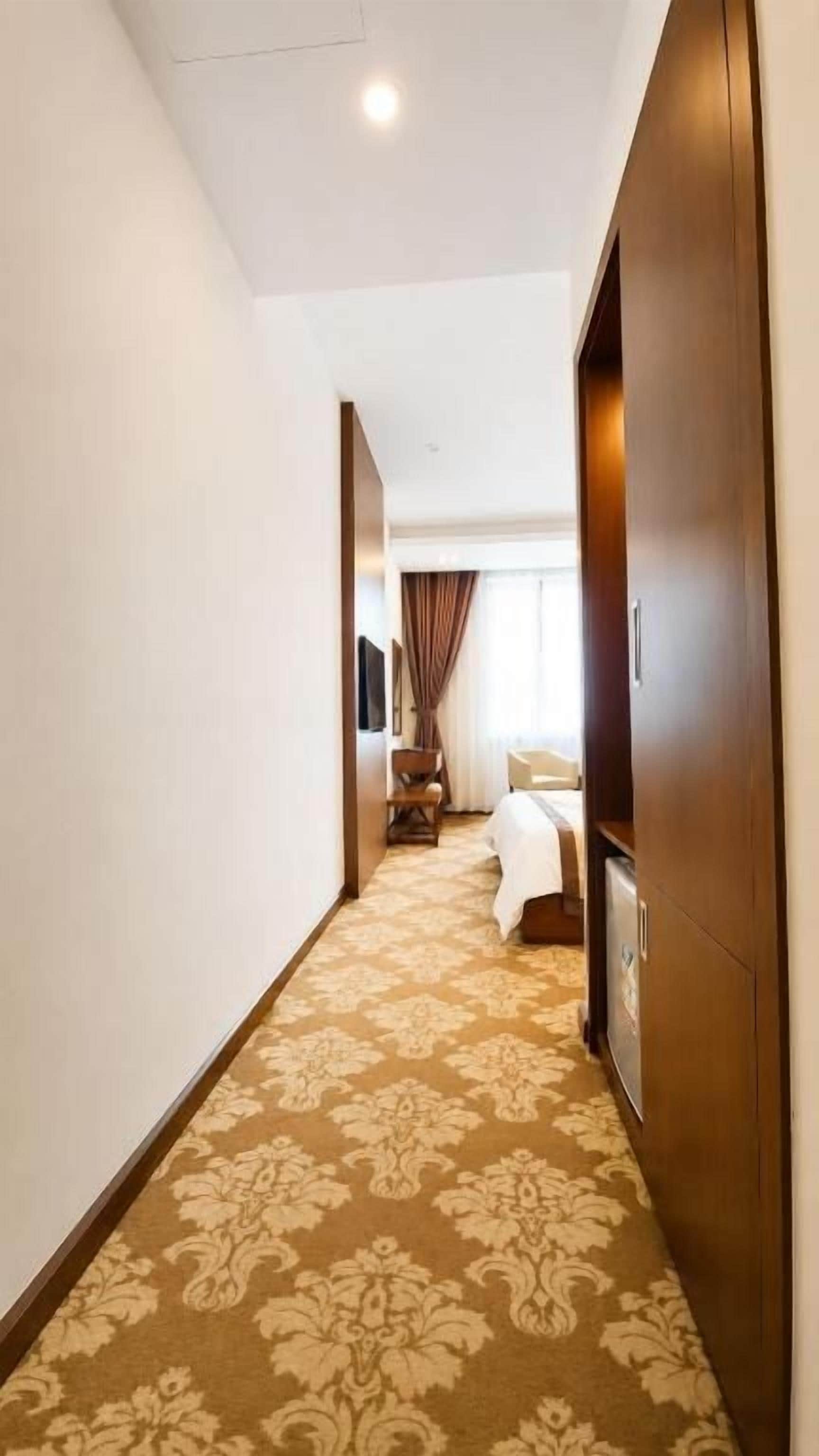 Ein Hotelgang mit Teppichboden, einem Bett und einem Kleiderschrank.