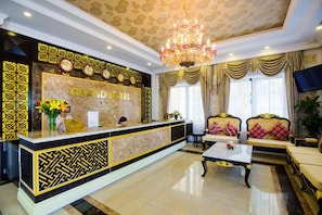A hotel reception area with a reception desk, seating area, and a chandelier.