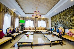 A luxurious lobby with a grand chandelier, ornate sofas, and a large wall mural.