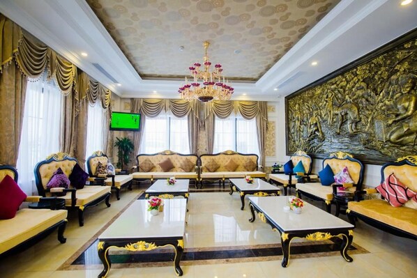 A luxurious lobby with a grand chandelier, ornate sofas, and a large wall mural.