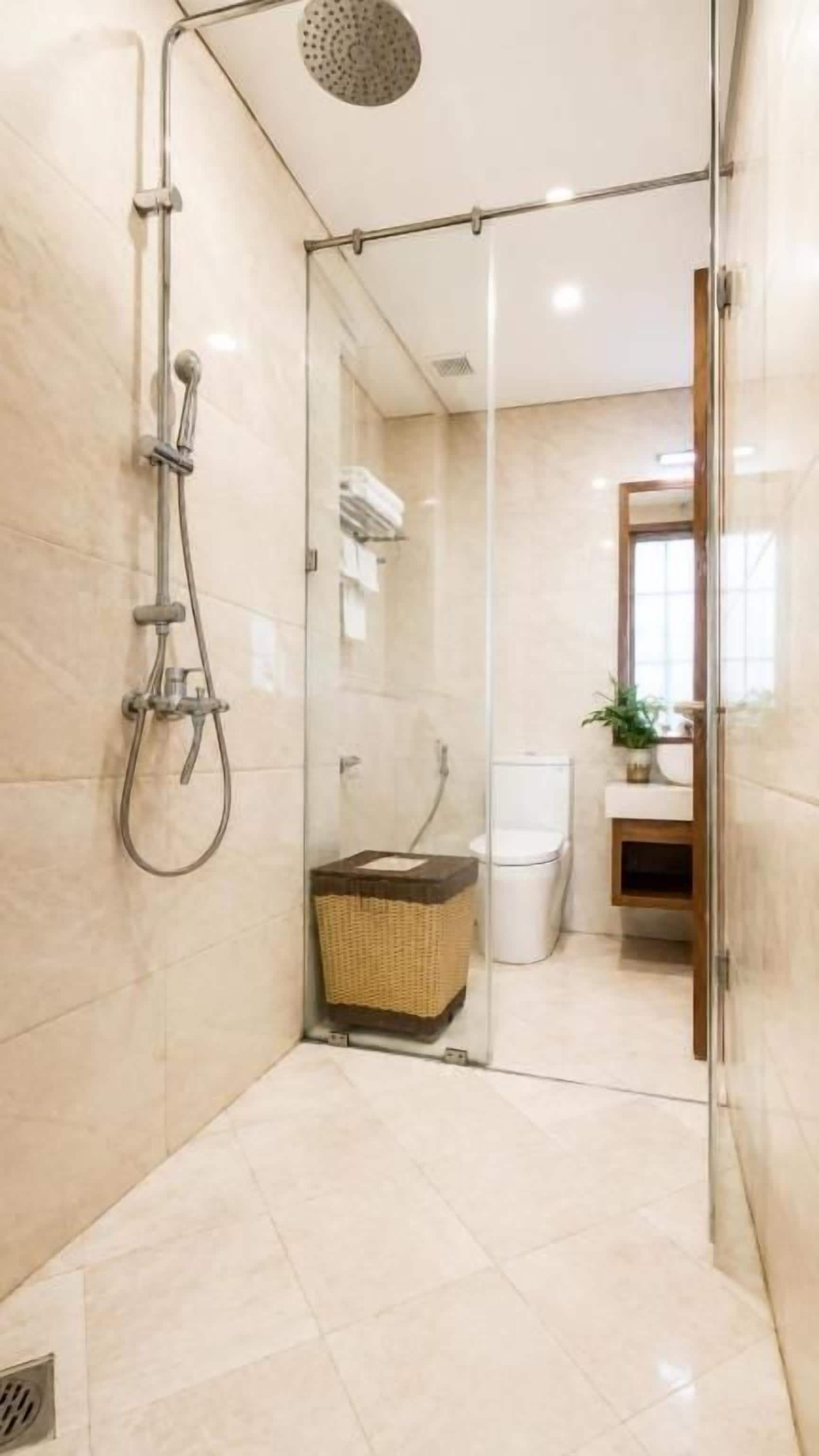 A modern bathroom with a glass shower enclosure, a visible toilet, and a wicker basket.