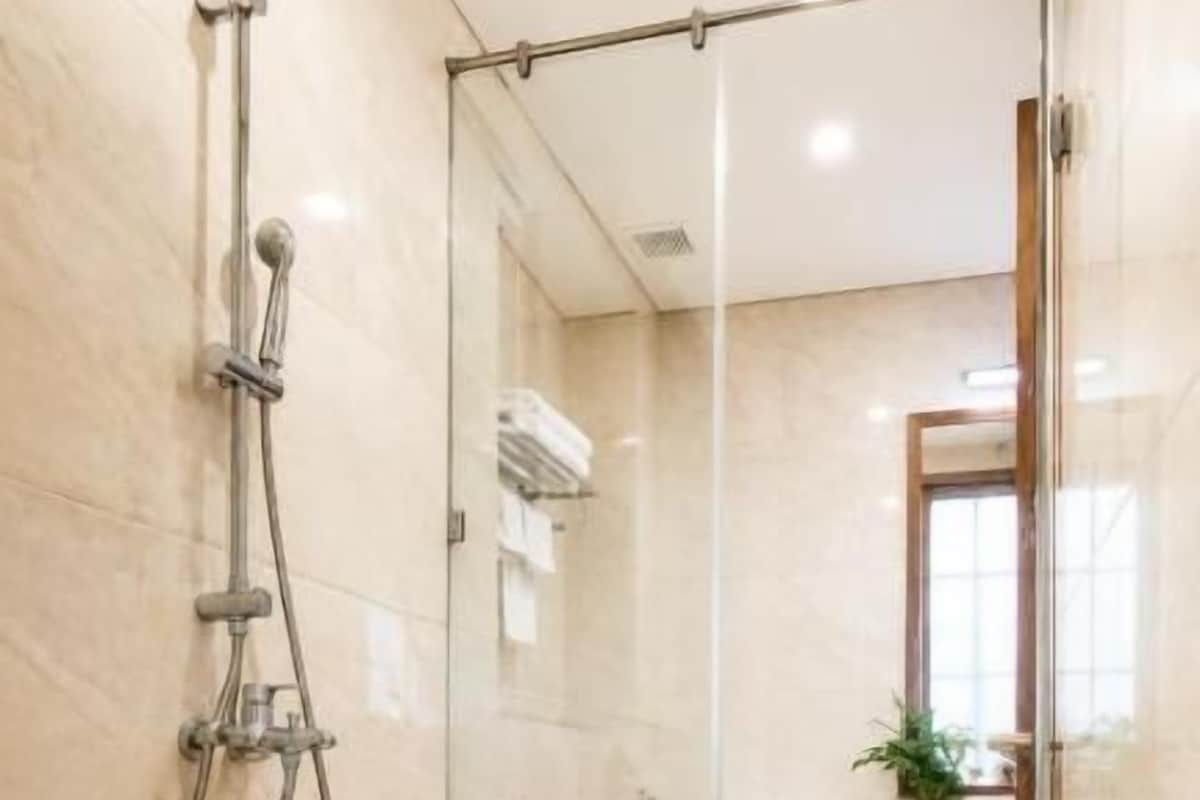 A modern bathroom with a glass shower enclosure, a visible toilet, and a wicker basket.