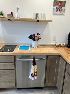 A kitchen with a stainless steel refrigerator, a wooden countertop, a blue cutting board, and a hanging kitchen towel. - Beautiful new and modern cabin with gorgeous Ninilchik River views. (Ninilchik)