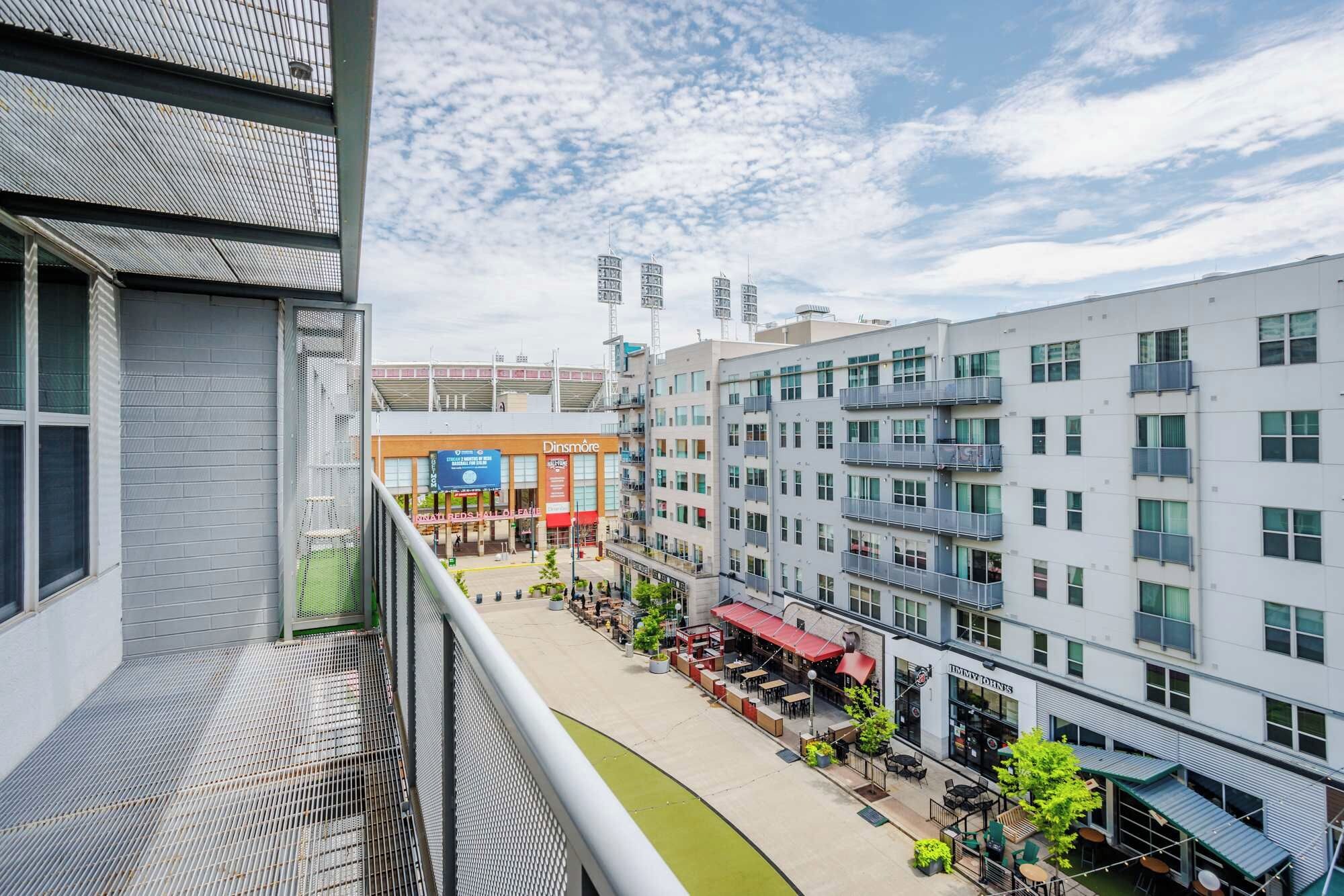 Un bâtiment urbain moderne à plusieurs étages, doté d’un espace extérieur couvert aménagé en terrasse et abritant un restaurant visible, appelé « Dinsmore ».