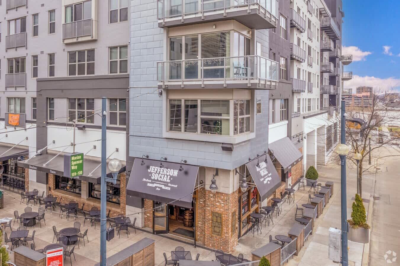 A multi-story building with a restaurant named "Jefferson Social" on the ground floor, featuring outdoor seating and a brick facade.