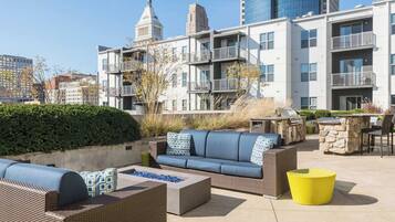 An outdoor patio area with seating, a fire pit, and a grill.
