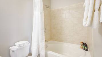 Une salle de bain avec une baignoire, des toilettes et un rideau de douche.