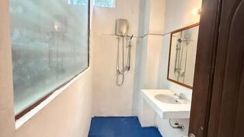 Un baño estrecho con piso azul, un lavamanos blanco y un espejo encima.