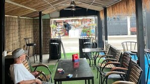 An outdoor seating area with tables and chairs, a ceiling fan, and a view of a street with shops. - White Castle (Krong Siem Reap)