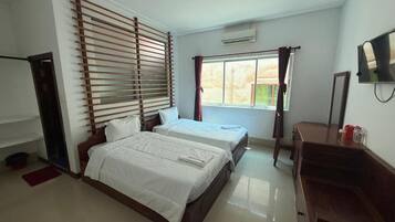 Un dormitorio con dos camas, cabecero de madera, televisor y ventana con cortinas.