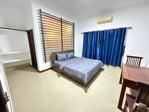 A bedroom with a bed, a table, and a chair. - White Castle (Siem Reap)