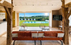 Ein modernes Wohnzimmer mit Blick auf einen Pool, einem Flachbildfernseher und einer Sitzecke mit zwei gepolsterten Bänken.