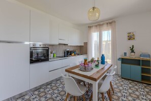 Eine moderne Küche mit weißen Schränken, einem Holztisch und einem blauen Schrank.