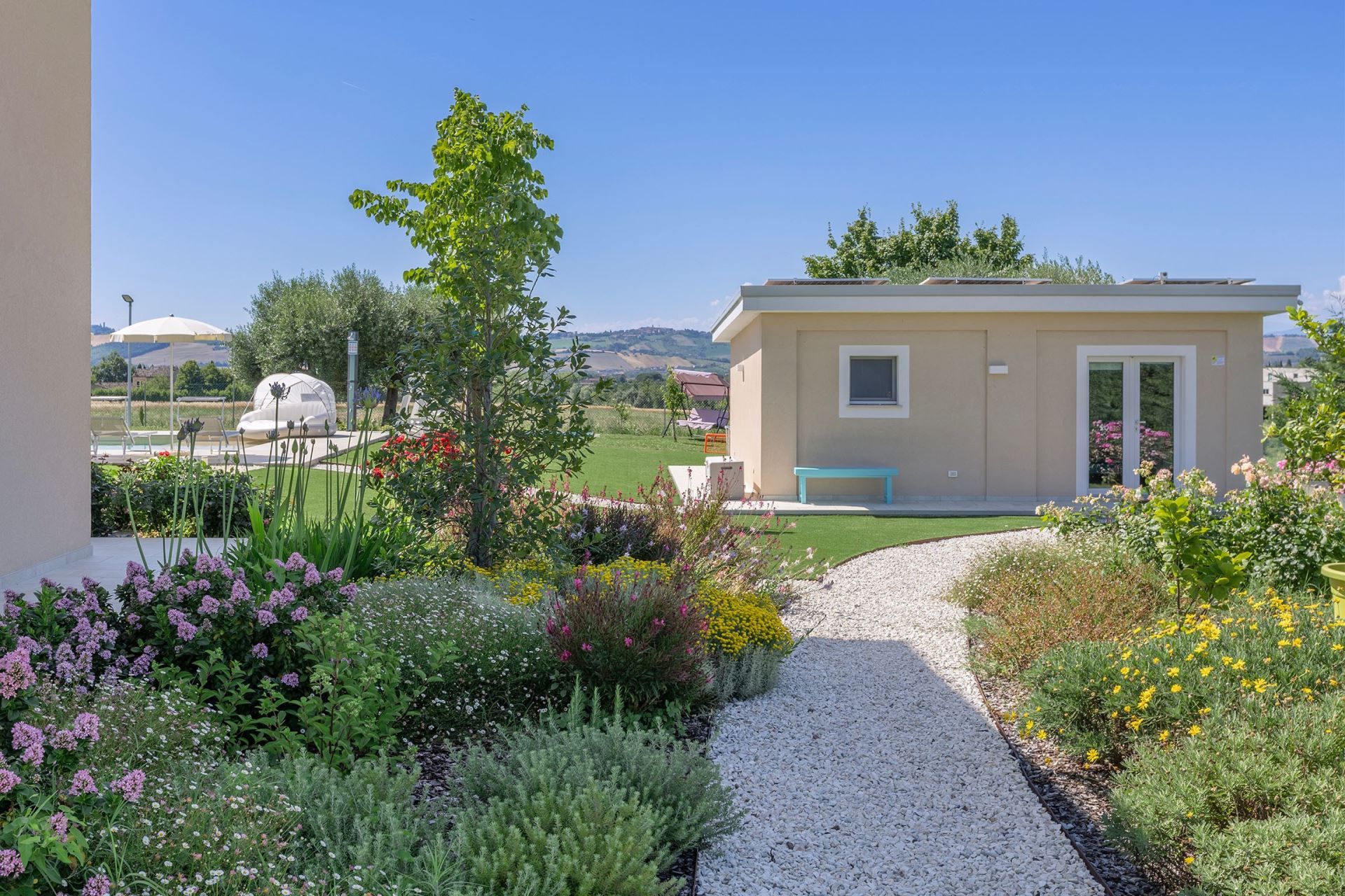 Ein Gartenweg führt zu einem Gebäude mit einer Bank und einer Tür.