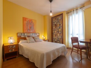 A hotel room with a bed, bedside tables, a chair, a table, a painting, and a curtain. - Mirador de San Felipe Neri (Málaga)