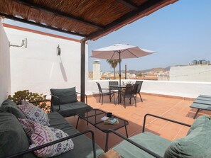 A covered outdoor seating area with a table, chairs, and a large umbrella. - Mirador de San Felipe Neri (Málaga)