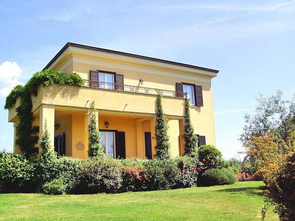 A two-story building with a balcony and a garden in front.