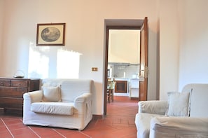 A living room with two sofas, a wooden dresser, and a framed picture on the wall.