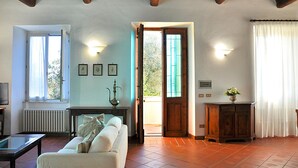 Un soggiorno con divano, tavolino, termosifone, televisore e una porta che dà sull'esterno.