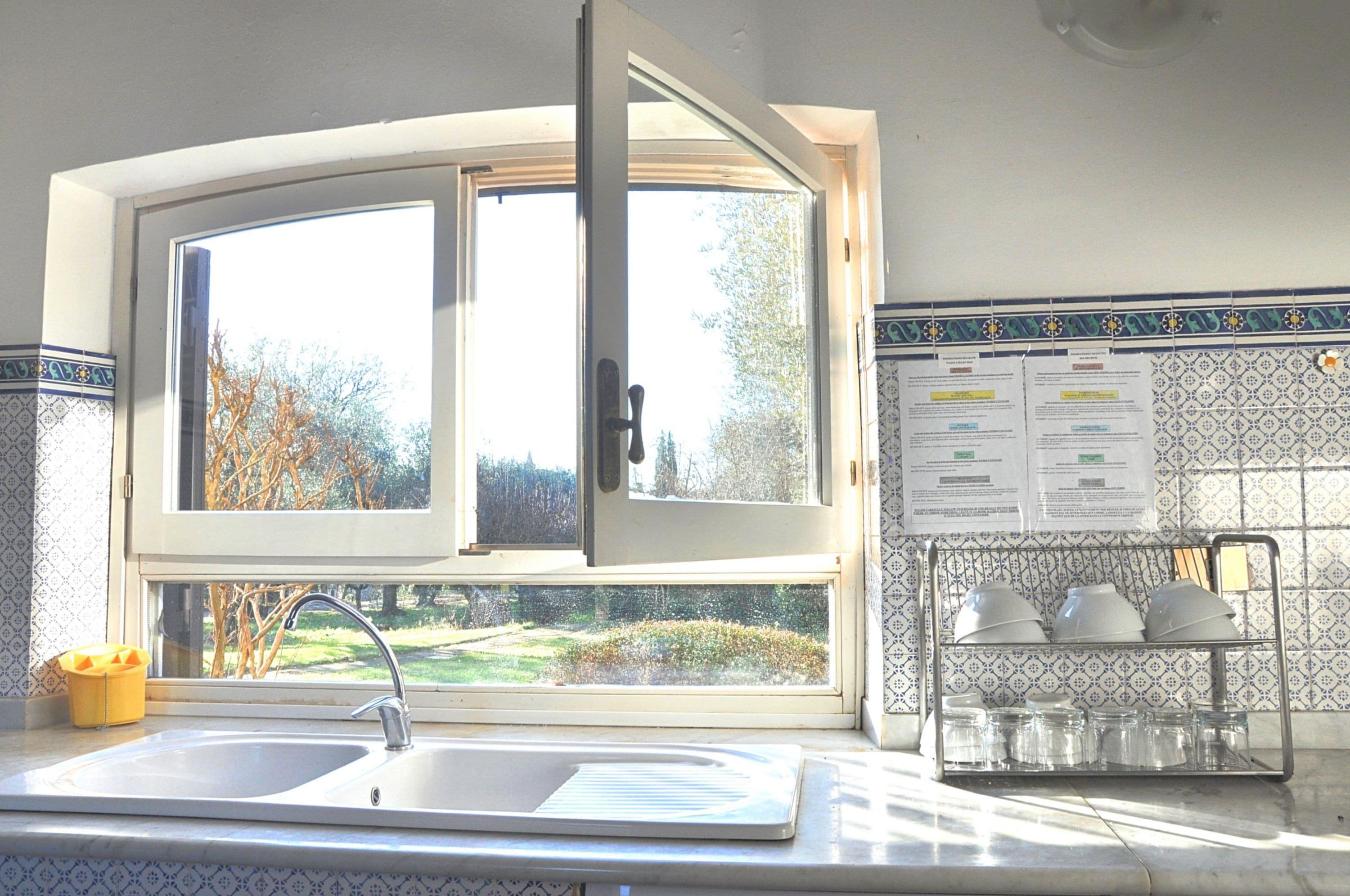 A kitchen with a large window, a sink, and a tiled backsplash.