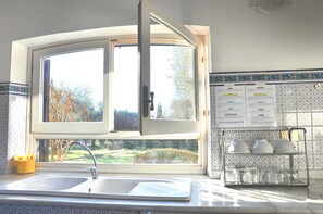 A kitchen with a large window, a sink, and a tiled backsplash.