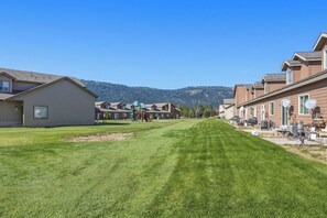 A residential area with houses, a playground, and a clear view of a forested mountain range. - The Donnelly Den | Tamarack Getaway, Game Room (Donnelly)