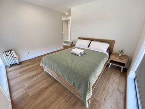 Ein Schlafzimmer mit einem Bett, einem Nachttisch, einer Heizung und einem Fenster.