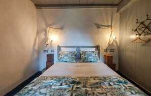 A bed with a tropical print bedspread, two wall-mounted nightstands, and two wall-mounted lamps. - Nice home in Les Gonds with private swimming pool, can be inside or outside (Les Gonds)