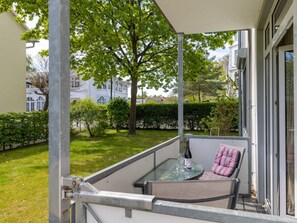 A balcony with a glass table, a chair, and a cushion. - 5, Residence Dunenstrasse (Binz)