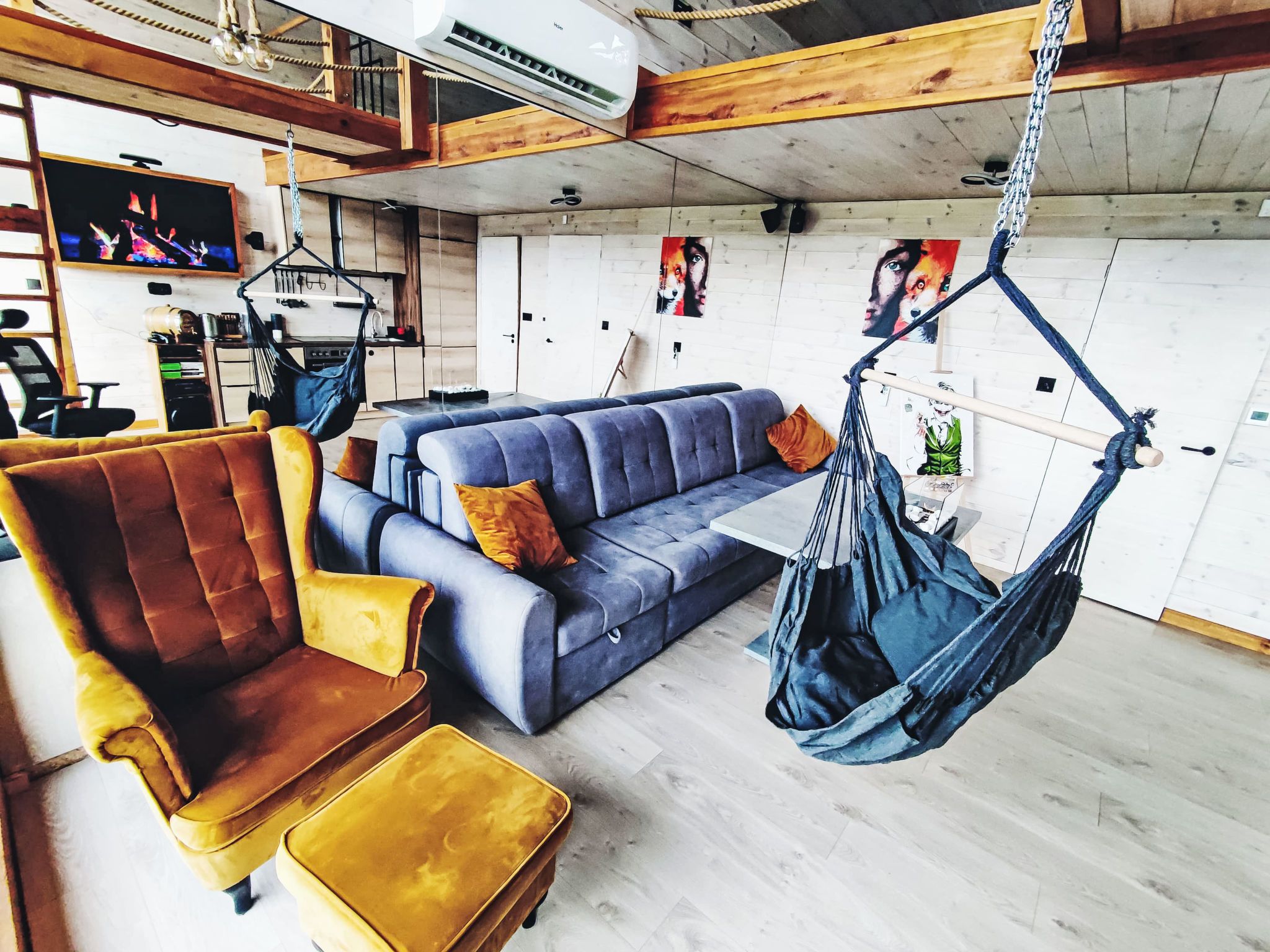 Un salon moderne comprenant un canapé, un fauteuil, un fauteuil suspendu et un téléviseur.