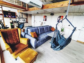 A modern living room with a sofa, a chair, a hanging chair, and a television.