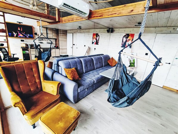 A modern living room with a sofa, a chair, a hanging chair, and a television.