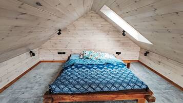 Een klein slaapkamer onder het dak met houten bed en dakraam.