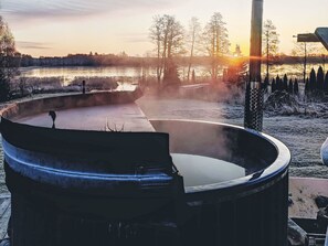 Un jacuzzi con vistas a un lago y árboles al atardecer.