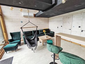 A modern lounge area with a hanging chair, sofas, and a wooden table.