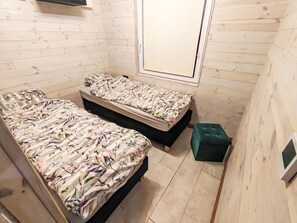 A small, compact room with two beds, a bench, and a window.