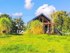 A modern house with a large glass window, surrounded by lush greenery and a clear sky. - Domki Sunia by Interhome (Worławki)