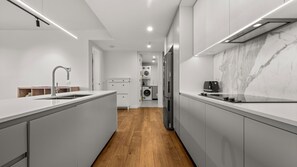Une cuisine moderne dotée d’un îlot central, d’appareils électroménagers intégrés et d’un dosseret en marbre.