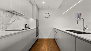 A modern kitchen with white cabinetry, a marble countertop, a built-in oven, and a stainless steel sink. - State Circle Stay | 10-Min Walk to Parliament (Forrest)