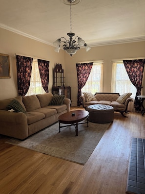 A living room with a brown sofa, a round coffee table, and a patterned rug. - 4bed 2ba bungalow for a relaxing stay just a short drive from museums, food &FSM (Fort Smith)