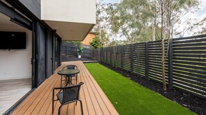 Eine Terrasses mit Holzdeck, einem Tisch und zwei Stühlen.