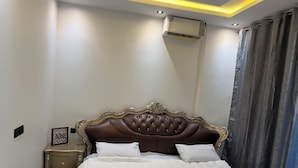 Ein Schlafzimmer mit einem großen Bett, einem Nachttisch, einem gerahmten Bild und einer wandmontierten Klimaanlage.