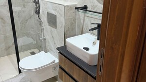 Ein modernes Badezimmer mit einer gläsernen Duschkabine, einer weißen Toilette und einem Holzwaschtisch mit Spiegel.