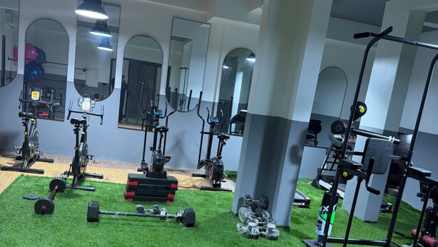 Ein Fitnessraum mit Trainingsgeräten, Kunstrasenböden und Spiegeln an den Wänden.