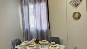 Ein Essbereich mit einem Tisch für vier Personen, gepolsterten Stühlen und einem modernen Deckenstil.